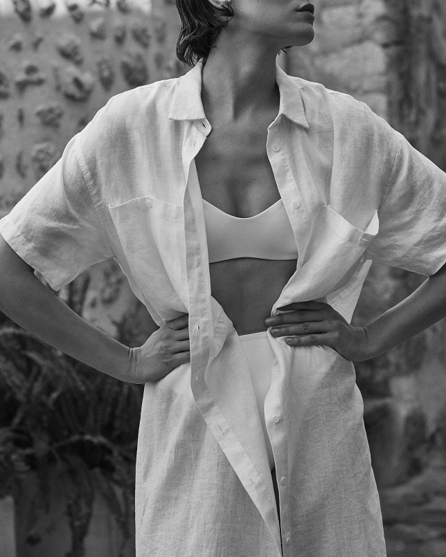 Person wearing a white Getaway shirt Dress over a La Plage top with a textured wall background