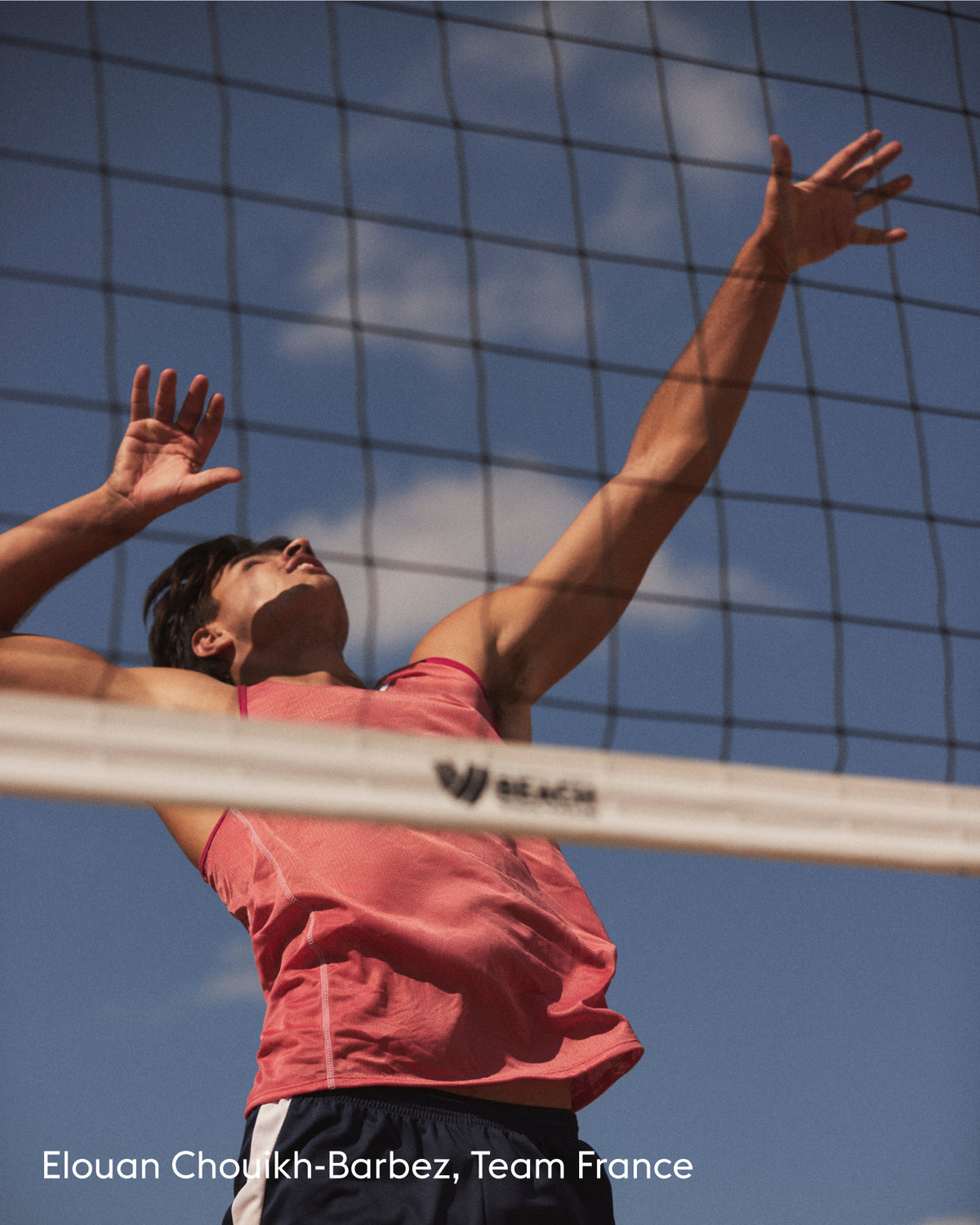 A male volleyball player in a pink tank top and dark shorts jumps above a net against a blue sky, with the text 'Elouan Choukh-Barbez, Team France' at the bottom left.
