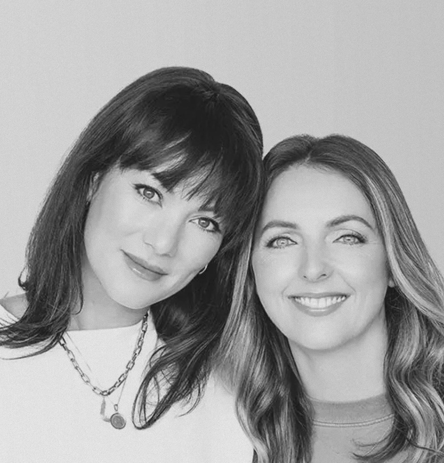 Two women posing for a black and white photo against a plain background