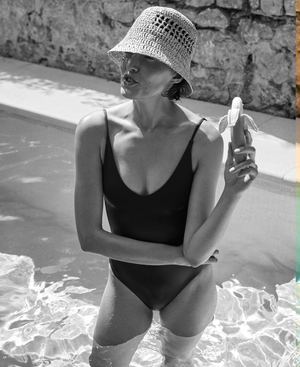 Woman in a black Sunday Suit and sun hat by a pool