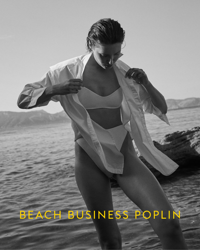 Person in a swimsuit with a white shirt on a beach, with 'Beach Business Poplin' text.