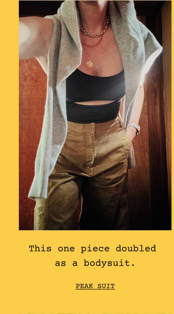 A woman wearing the Peak Suit in Jet, shown in a mirror-style selfie with text below reading 'This one piece doubled as a bodysuit.' and 'PEAK SUIT' on a yellow background.